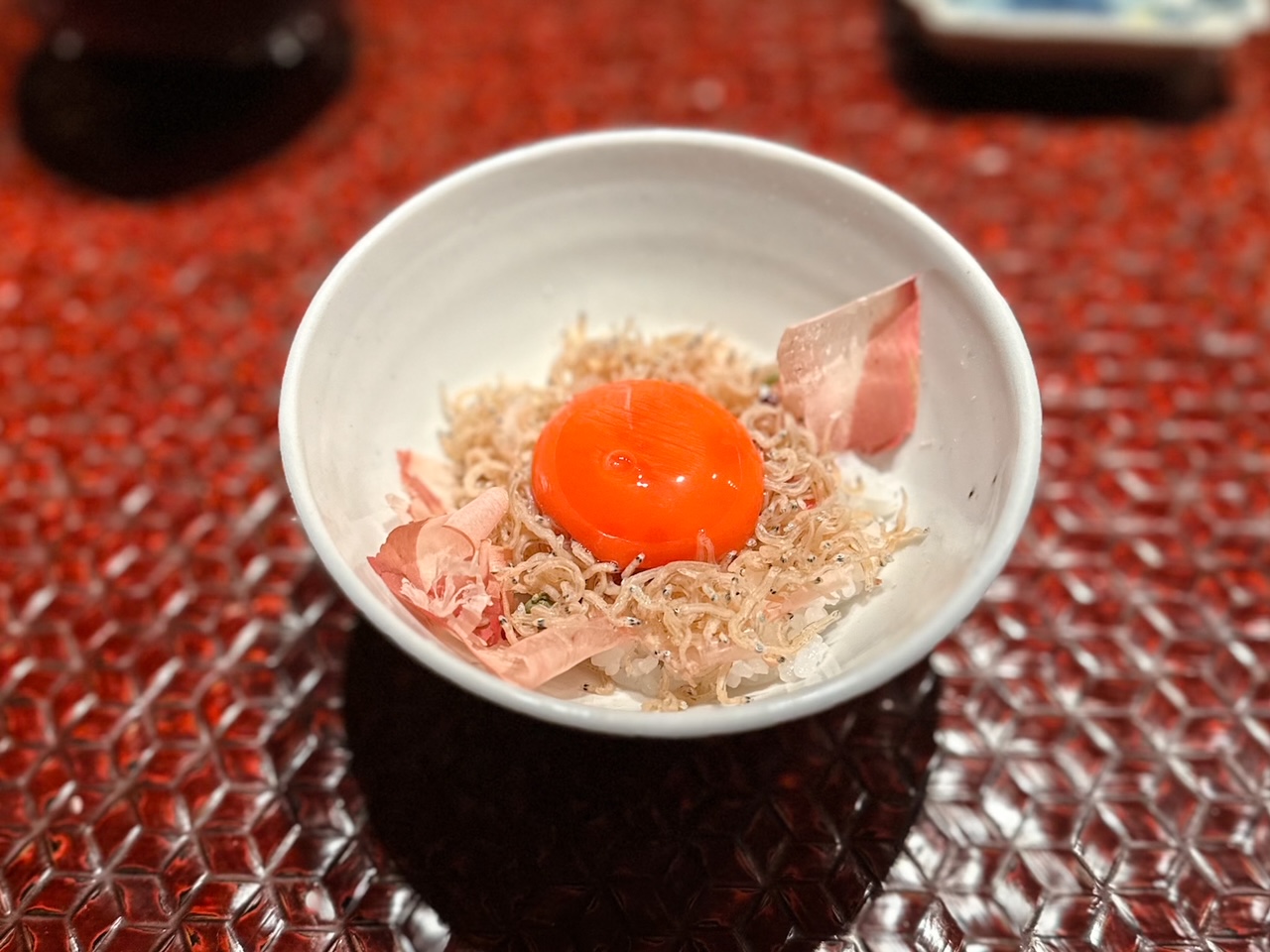 Piccole sardine e pepe sansho su riso, katsuobushi e tuorlo d'uovo.
