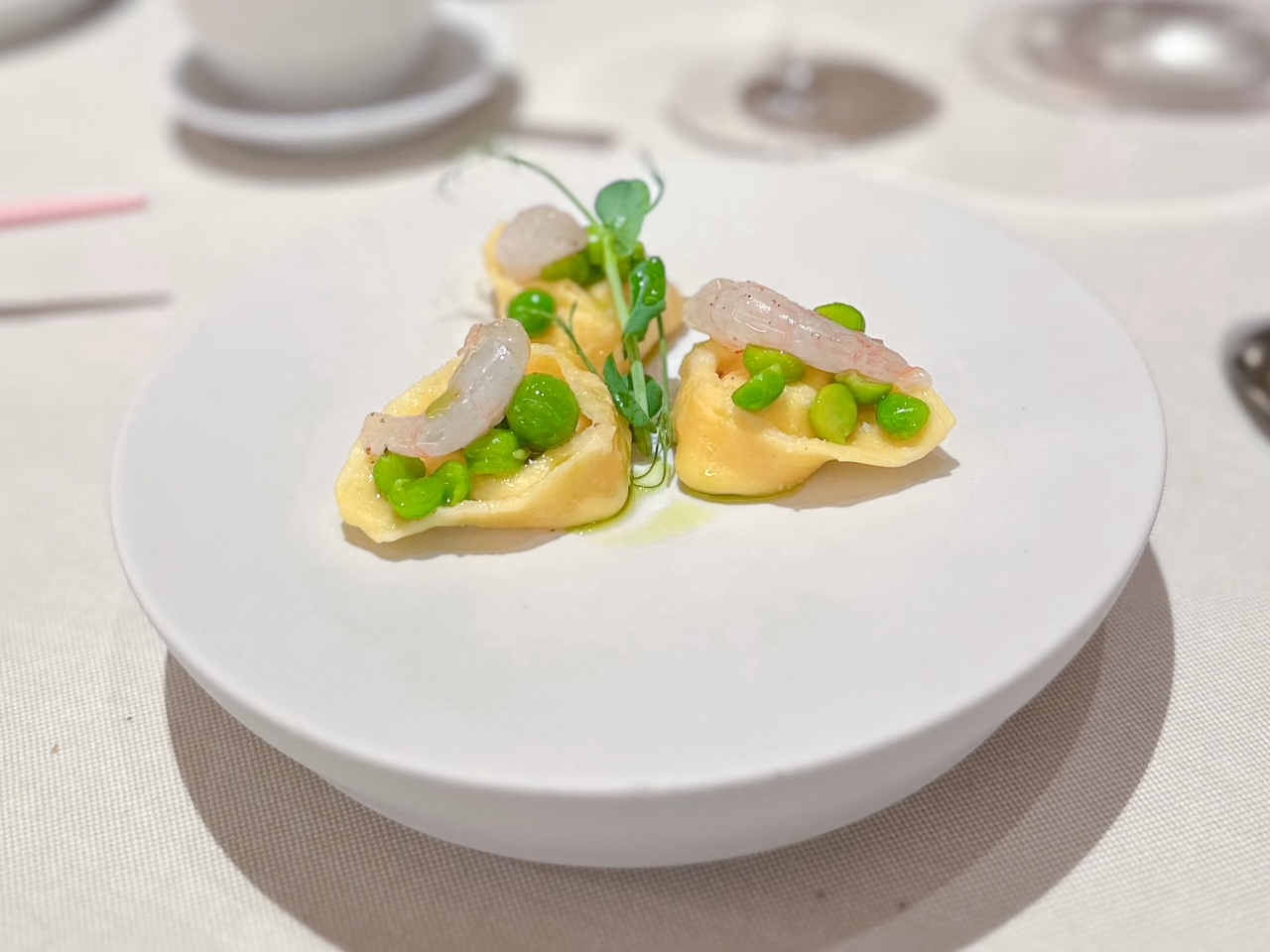 Ravioli al latte di capra cagliato, acqua di piselli e prosciutto, gamberi rosa, serviti al ristorante 12 apostoli