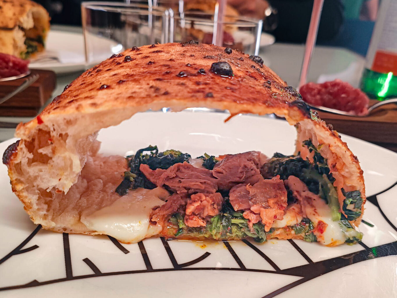 Agnello e friarelli, con la carne in versione “pulled” della pizzeria Confine.