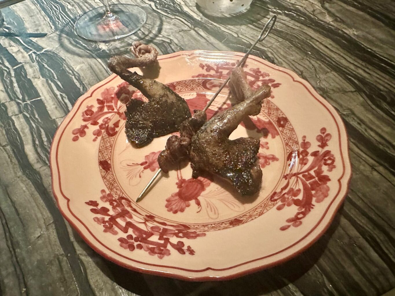 Piccione alla brace: cosce e spiedino di interiora.
