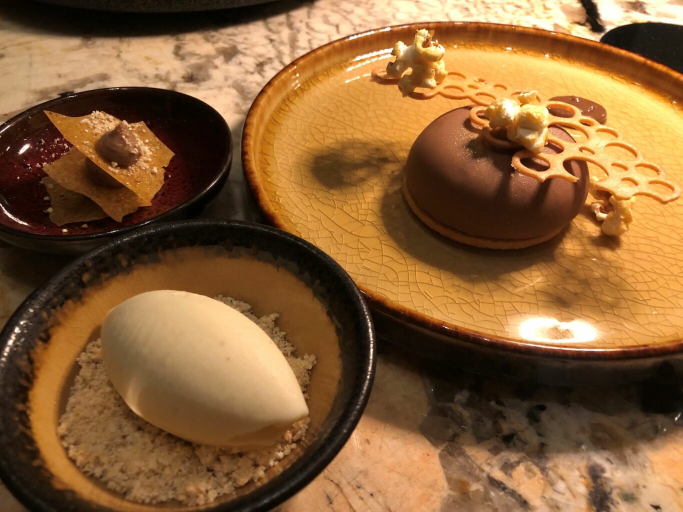 Mousse al cioccolato caramellato e noci pecan bottone di cioccolato allo yuzu, millefoglie con farina di mais e caramello Gelato al pop corn. Un fantastico dessert dell'Iyo restaurant.
