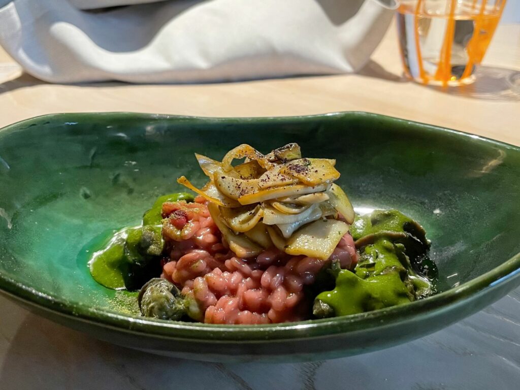 Risotto al vino rosso con lumache all’alloro, funghi scottati e polvere di mirtilli – Inverno 2024.