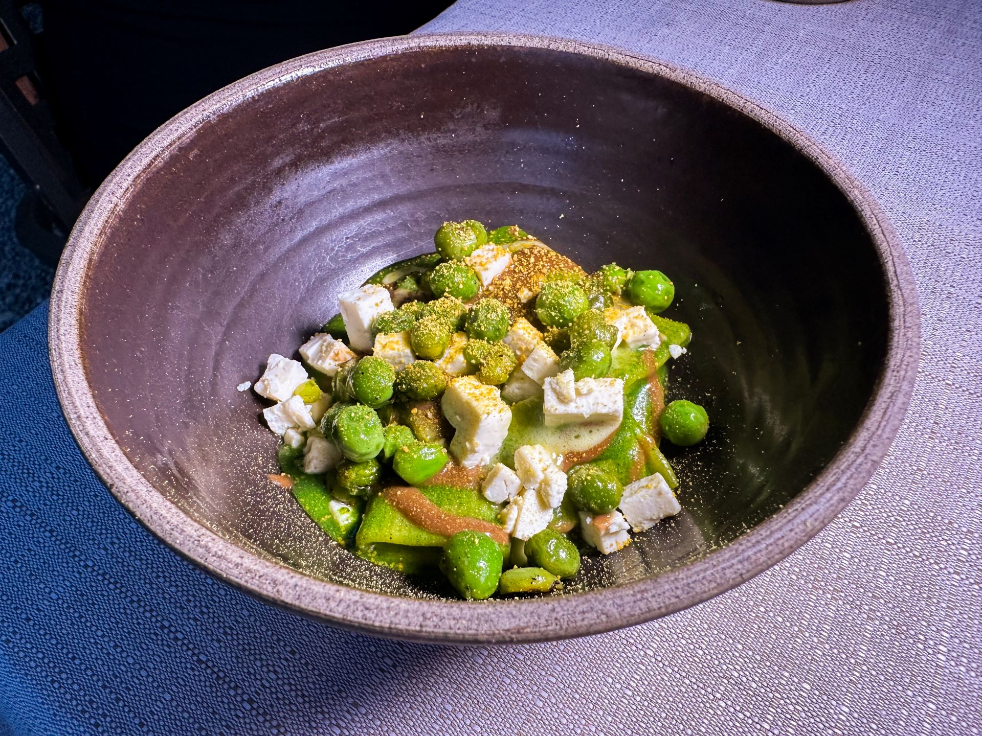 Mezze maniche cotte in acqua di prato, salsa aglio nero gentile, pesto di rucola, mascherpa, polline e piselli freschi alla brace.