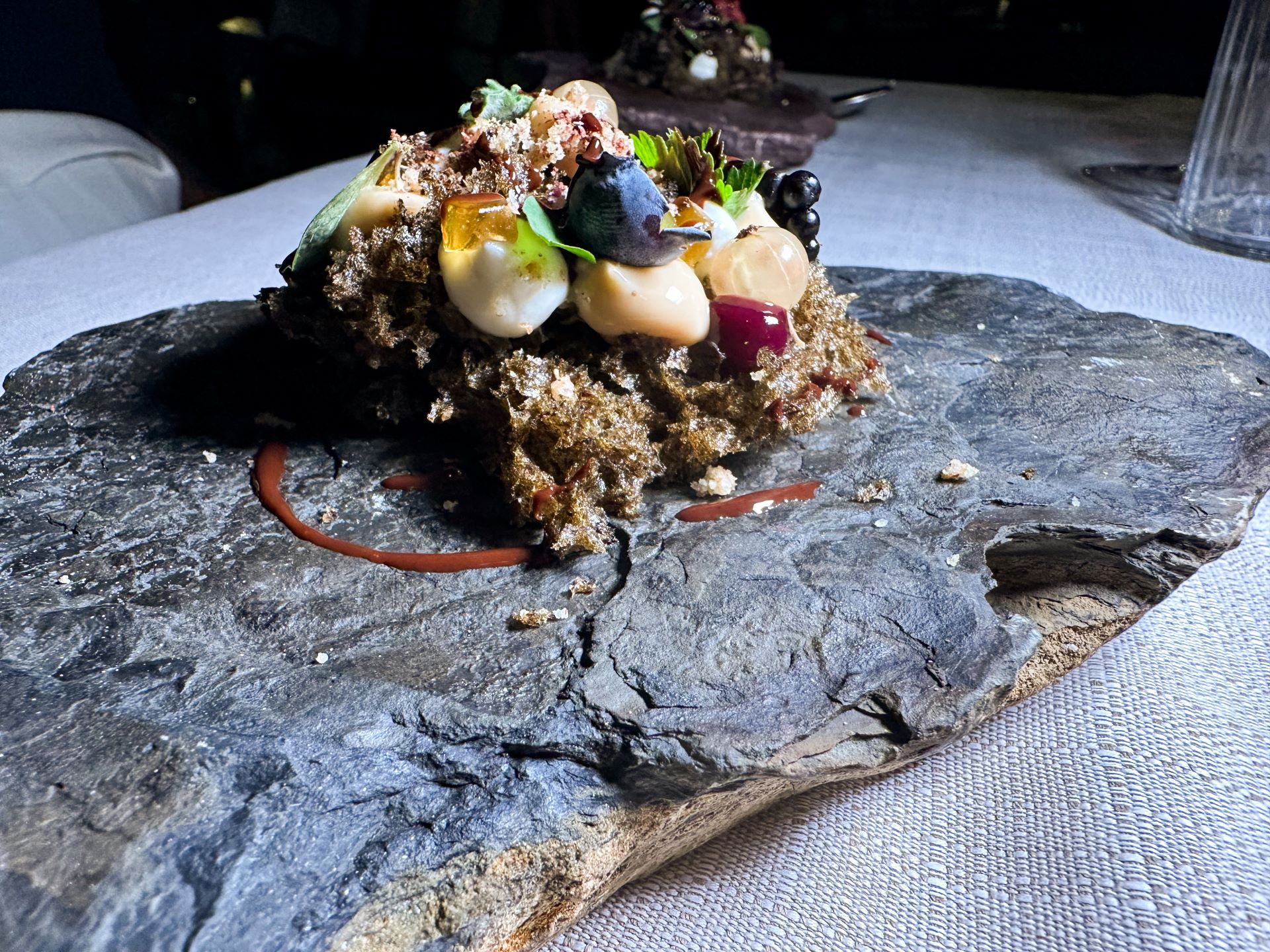 Spugna di muschio, cremoso al mirtillo, yogurt, namelaka al cioccolato e olio essenziale di abete, gelatina all'amaro del ferdy, crumble al grano saraceno e funghi, grue di cioccolato.