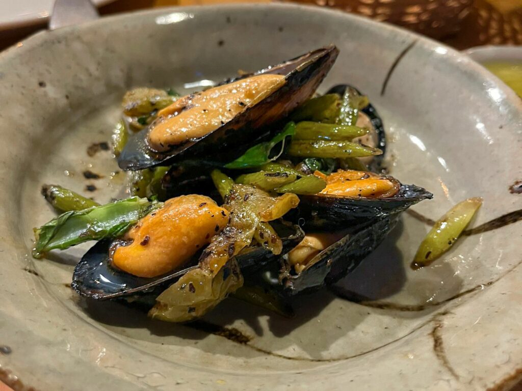 Cozze di Scardovari saltate, talli di aglio, prugne selvatiche, peperoncino Isot Biber e foglie di senape.