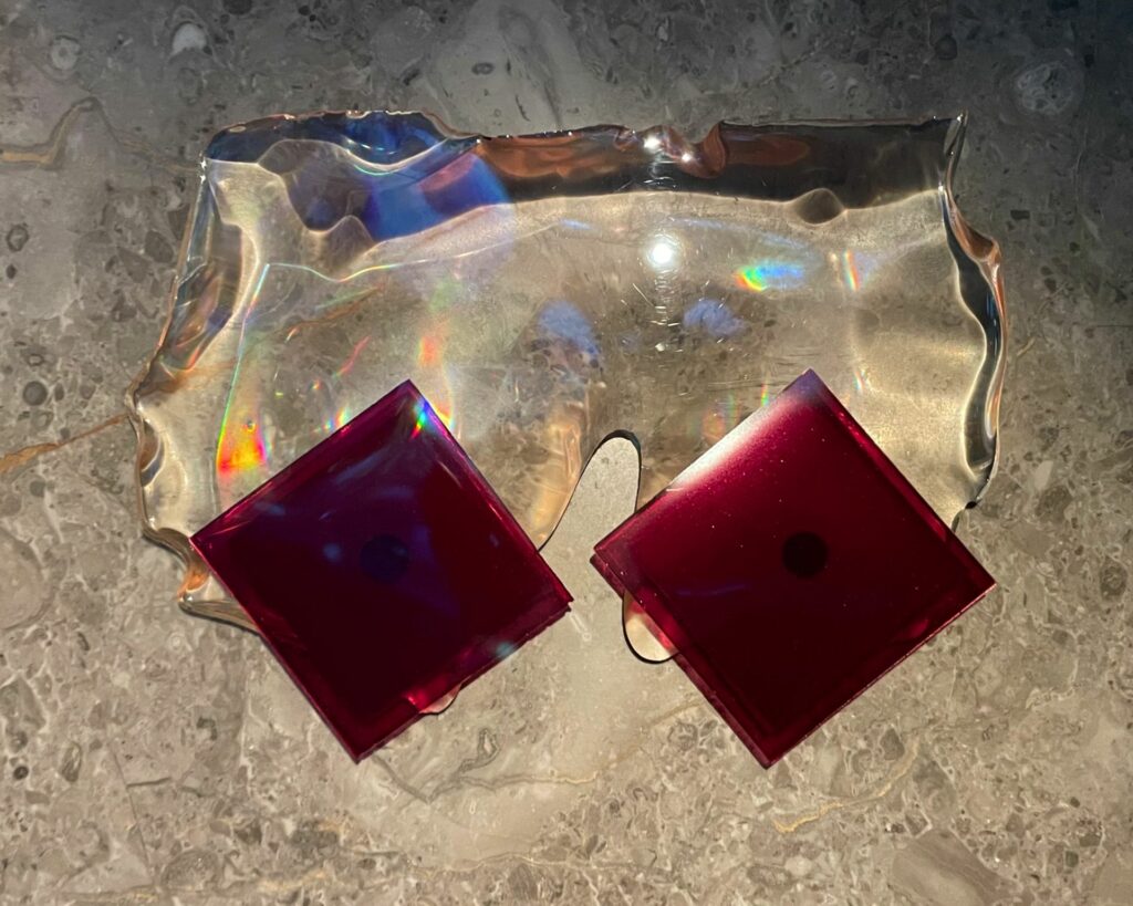 Reflection. L'effetto arcobaleno è creato da microscopiche scanalature nello "specchio" di ribes nero che diffrange la luce. Sotto lo specchio, ci sono strati di gel di ribes nero, croccante di cioccolato al 70%, gelato alla vaniglia con olio d'oliva e croccante di cacao.