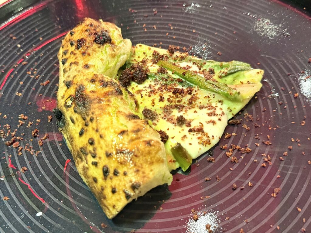 Pizza agli asparagi: fior di latte, crema di asparagi, asparago bianco fermentato, asparago verde saltato, crumble di bacon della pizzeria Quattro Quarti.