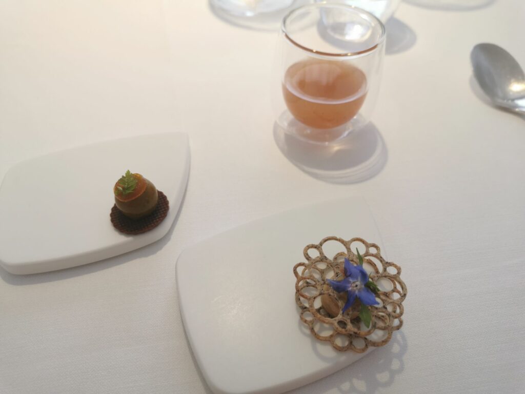 Tuile di farina di grano saraceno, humus di ceci con colatura di alici. Tartelletta di farina di castagna, bon bon di fois gras di pesce e frutto della passione. A concludere un gin con pinolo, curry rosso e banana chiarificata.