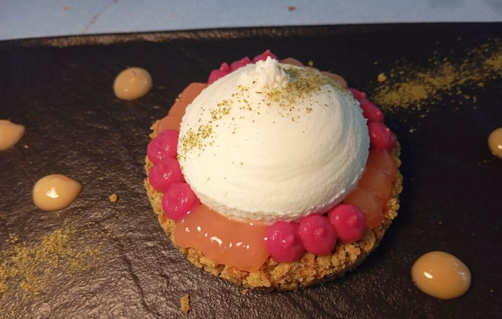 Crumble di biscotto, gel di melograno, chantilly di ricotta di pecora e rosmarino in polvere.