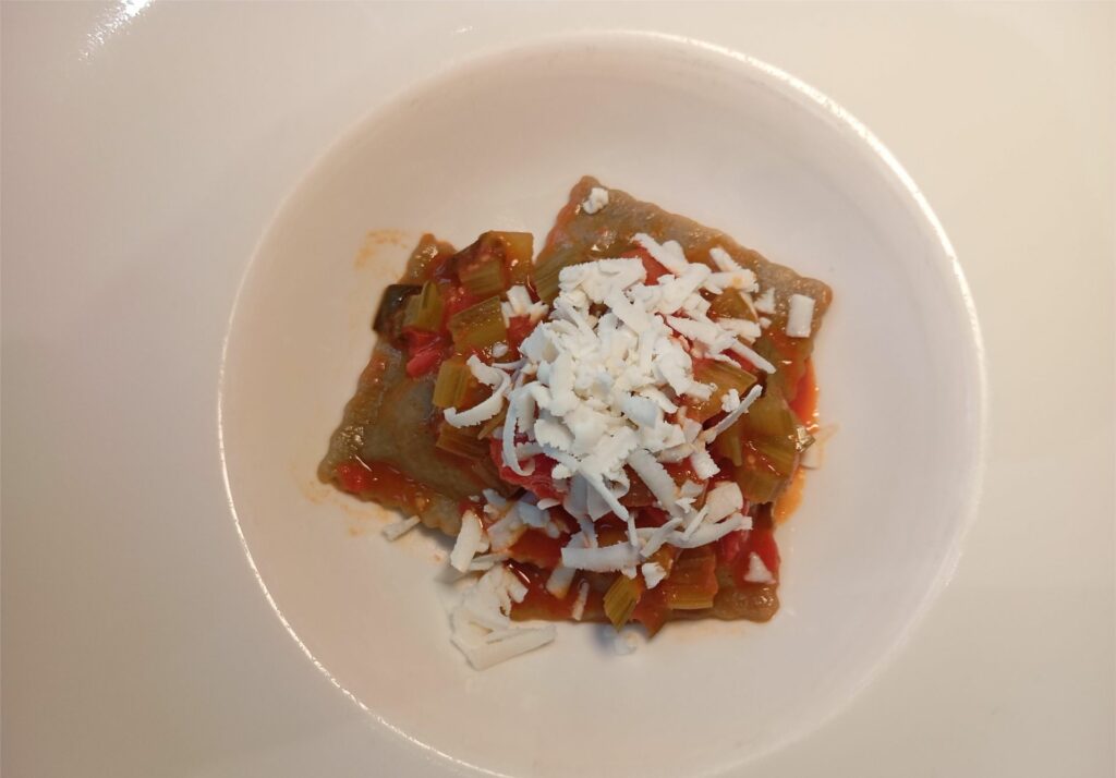 Ravioli farciti con brasato di suino e foglie dell'orto con pomodorini, bietola e ricotta salata.