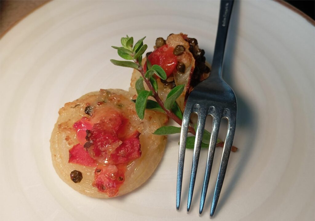Cipolle gratinate con capperi e pomodoro della trattoria Antichi Sapori.
