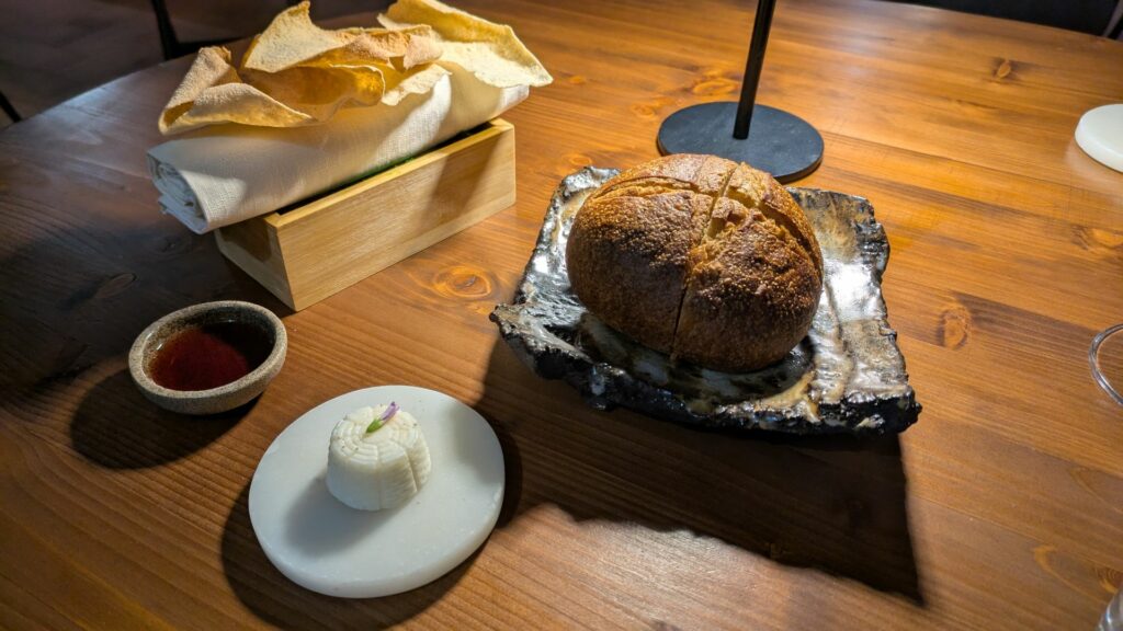 Servizio del pane di contatto. Da segnalare il carasau accompagnato da aceto di Montepulciano e more.
