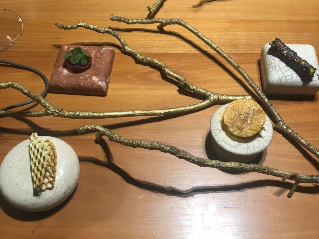 Amuse bouche: il giardino dello chef
Cannolo di shiso rosso ripieno di dahl di lenticchie, gel di lime e furikake
Opaline alla barbabietola foglia di senape tartare di rapa rossa
Nido d’ape con nasturzio, crema di broccolo romanesco, broccoli con olio al cavolo nero, polvere d’Espelette
Sfoglie di ananas disidratate ripiene di chutney di mele renette, scalogno, crema di cocco e lime