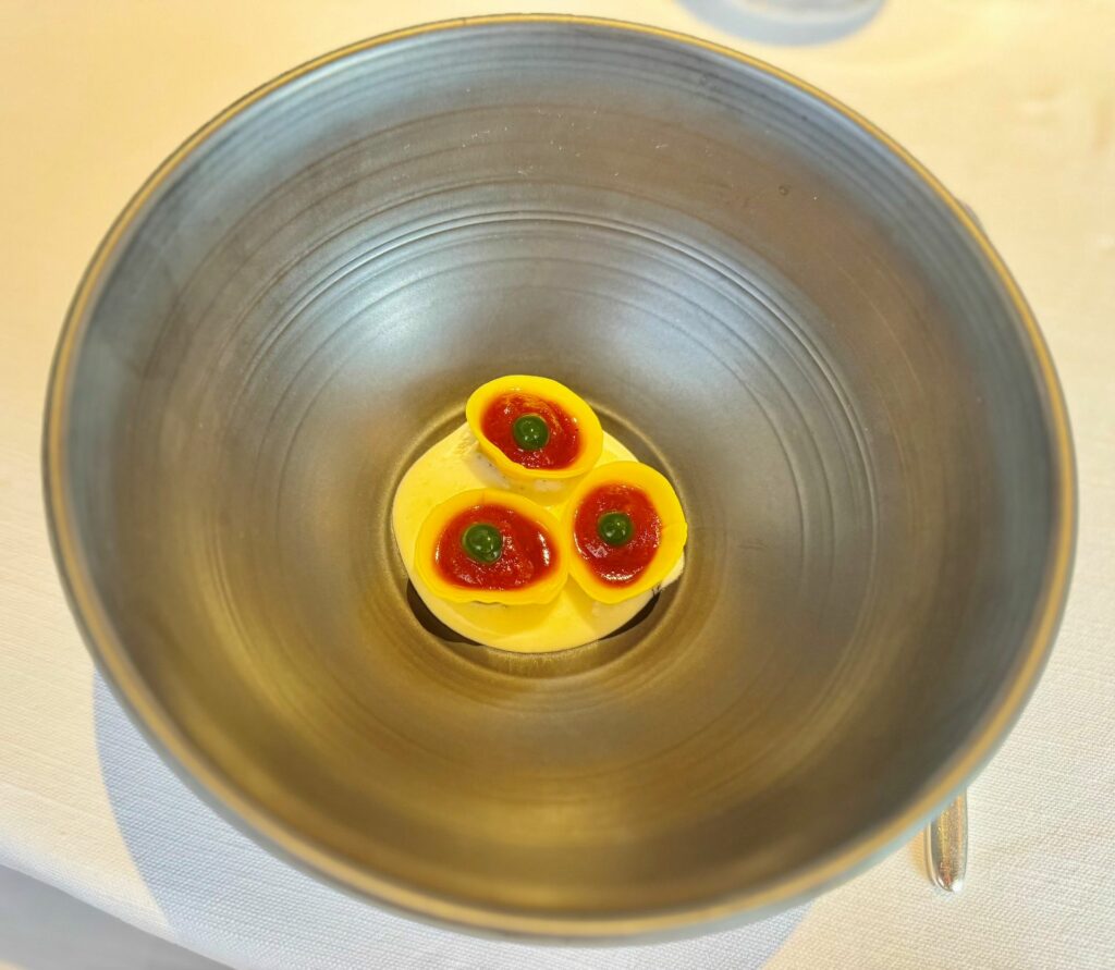 Napoli incontra l’Emilia: tortelli su spuma di parmigiano reggiano, farciti con ragù napoletano e
conditi con salsa di pomodoro e gel al basilico.