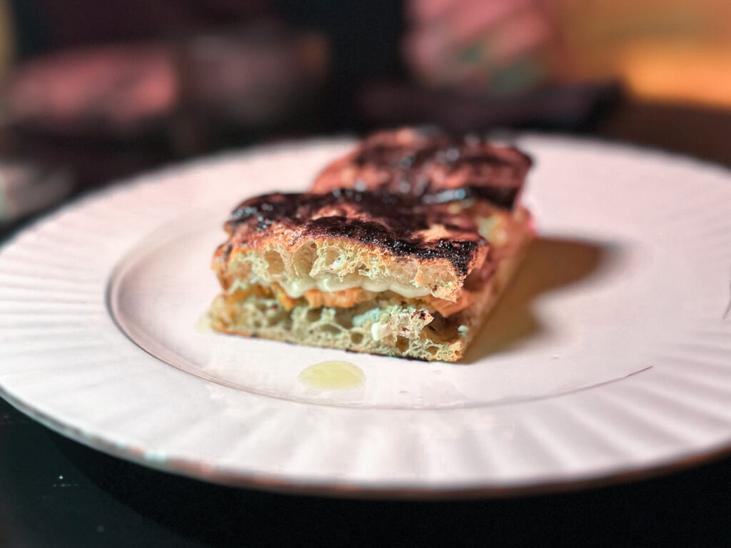 Pig: focaccia con pancetta di maiale nero, ripiena con carne di maiale, maionese barricata, crema di cotenna sulla crosta e cacao amaro di Campana 12