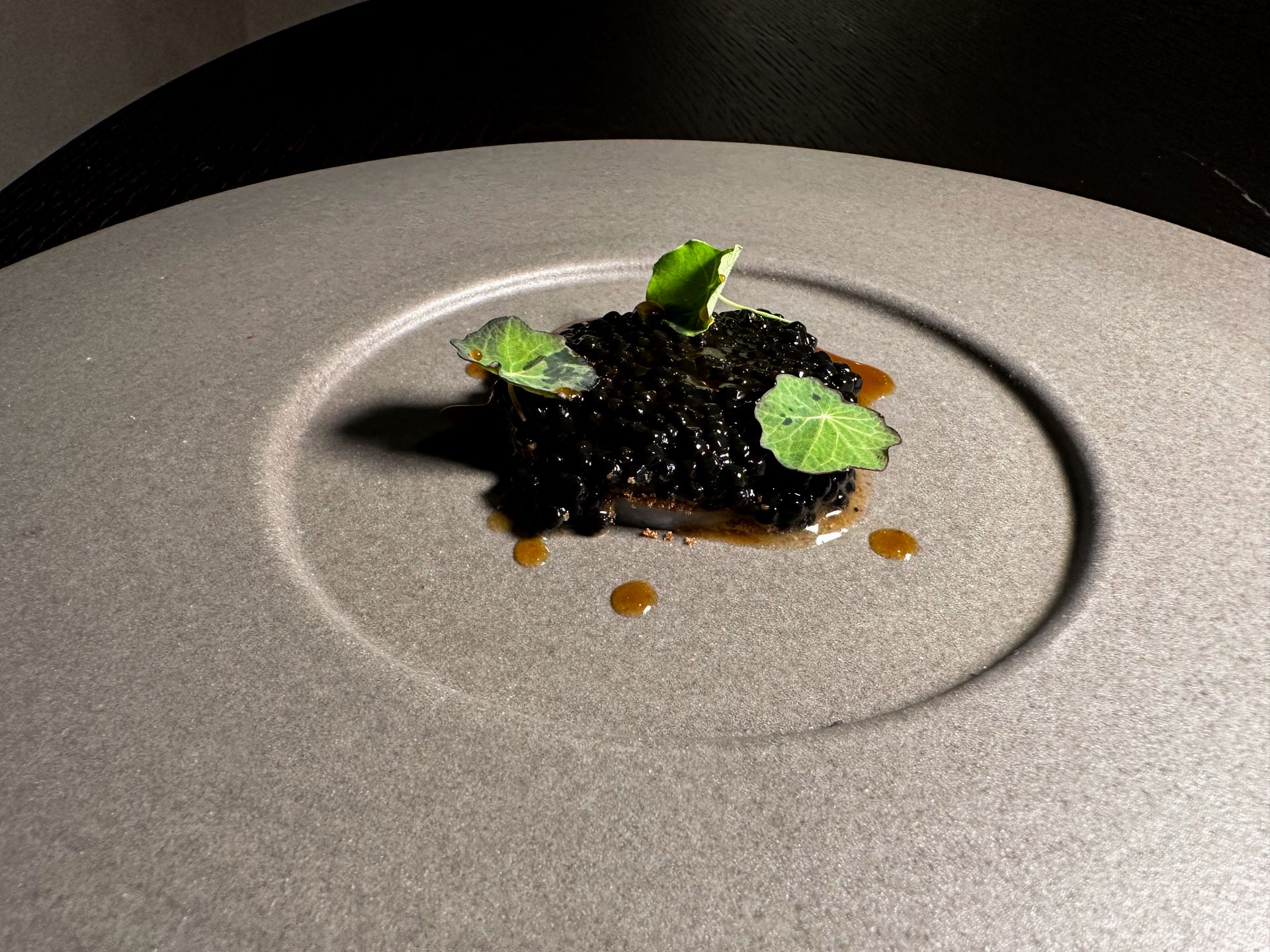 Velo di calamaro, polvere di carpaccio di bufala rosolato, caviale di tartufo nero, nasturzio, olio al peperone crusco, estratto di calamaro, fondo di bufala.