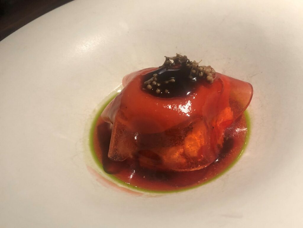 Fragoline di Nemi, sorbetto, gelatina, fiori di sambuco sottaceto, ganache all’anice stellato e cioccolato bianco, salsa di aceto balsamico all’aglio nero.