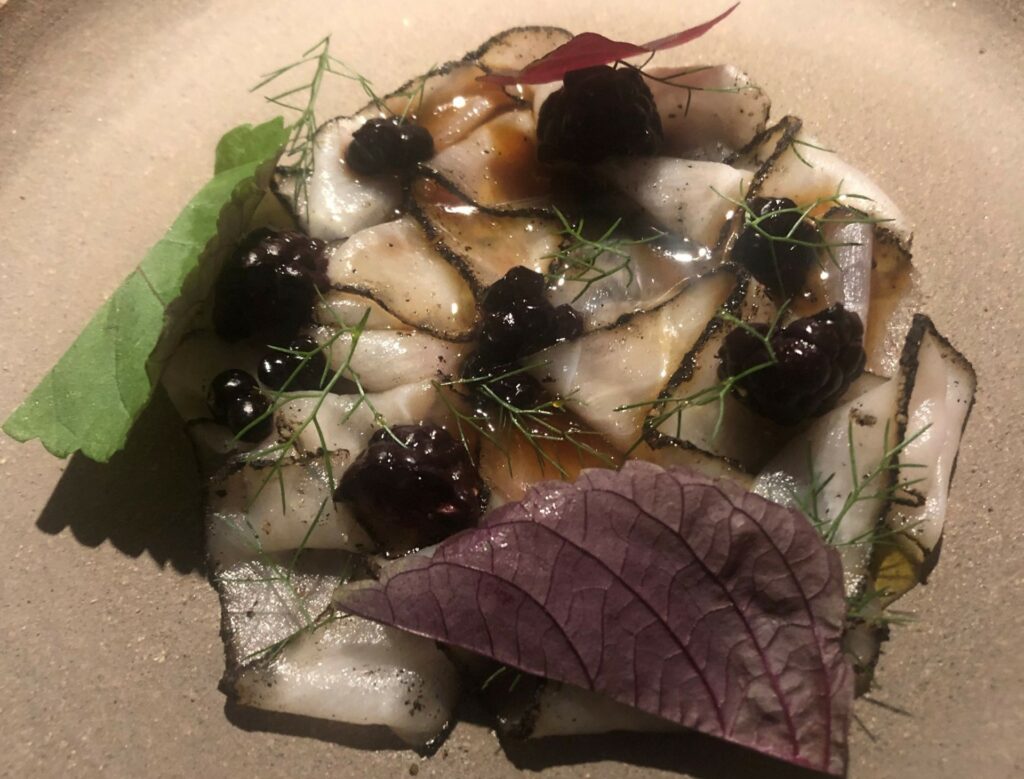 Storione disidratato e stagionato con squisite more, bacche di ginepro e salsa sapida ottenuto dalla lattofermentazione del pane di segale ammuffito.