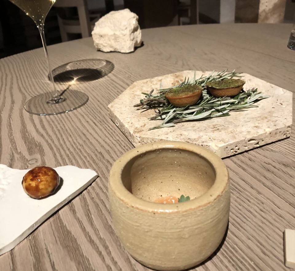 Amuse bouche di Nomos Ante: tartelletta alla cipolla, mini bun con salsiccia granita di pomodoro e semi di pomodoro bbq