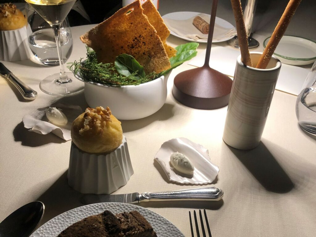 Pane: grissini all’olio, carta musica, panino al formaggio glassato con miele e noci, pane di miso e farina ai sette cereali, burro al caramello e sale maldon.