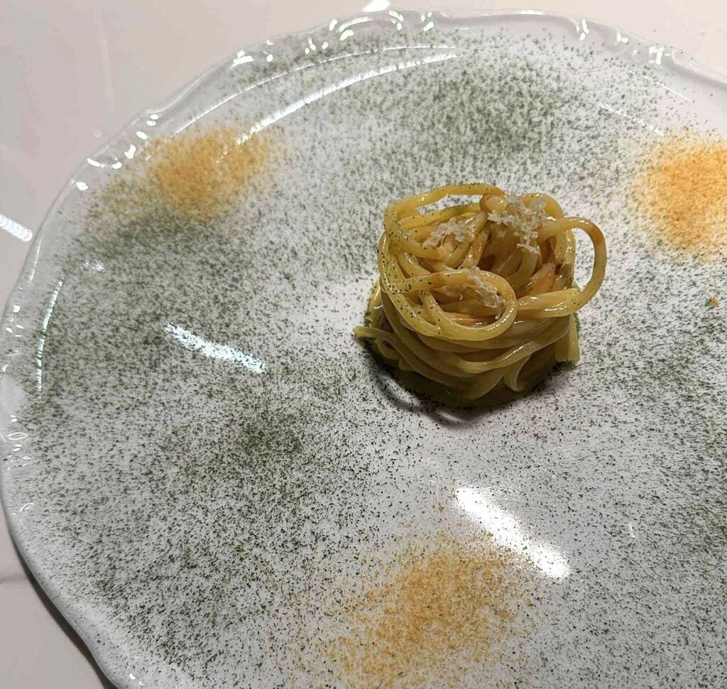 Spaghetti alla chitarra freschi serviti freddi con succo di melone fermentato, kefir di melone, melone salato e in polvere, olio di fico, sambuco fermentato, olio essenziale di luppolo, riccio di mare.