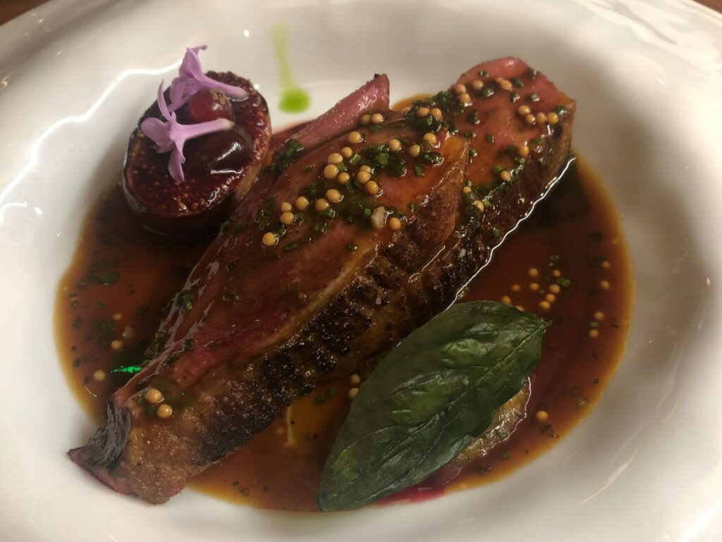 Anatra caramellata, fico arrostito, riduzione con senape, ribes e mirabella, olio di foglie di fico