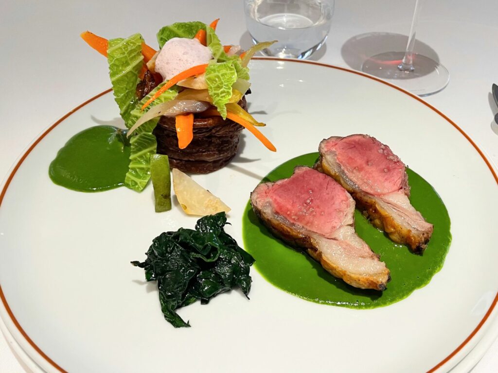 Carré d’agnello, salsa all’aglio orsino, vol au vent al cacao amaro ripieno di verdure dell’orto e spinaci agli agrumi [febbraio 2025]