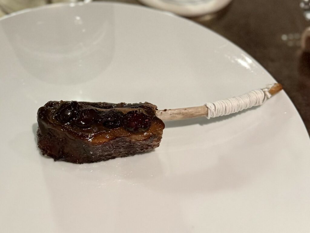 Costina di cinghiale con salsa barbeque, aglio nero, chutney di mirtillo e timo.