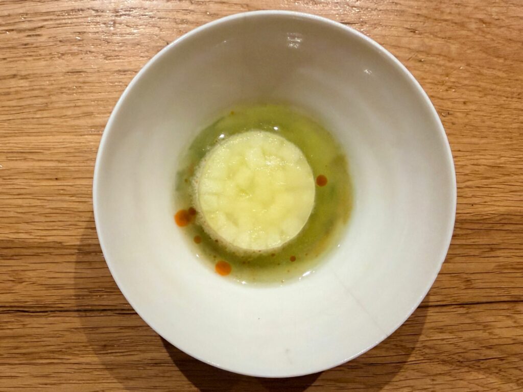 Cubo di ghiaccio alla mela verde, acqua di mela al curry verde, spray di gin agli agrumi.