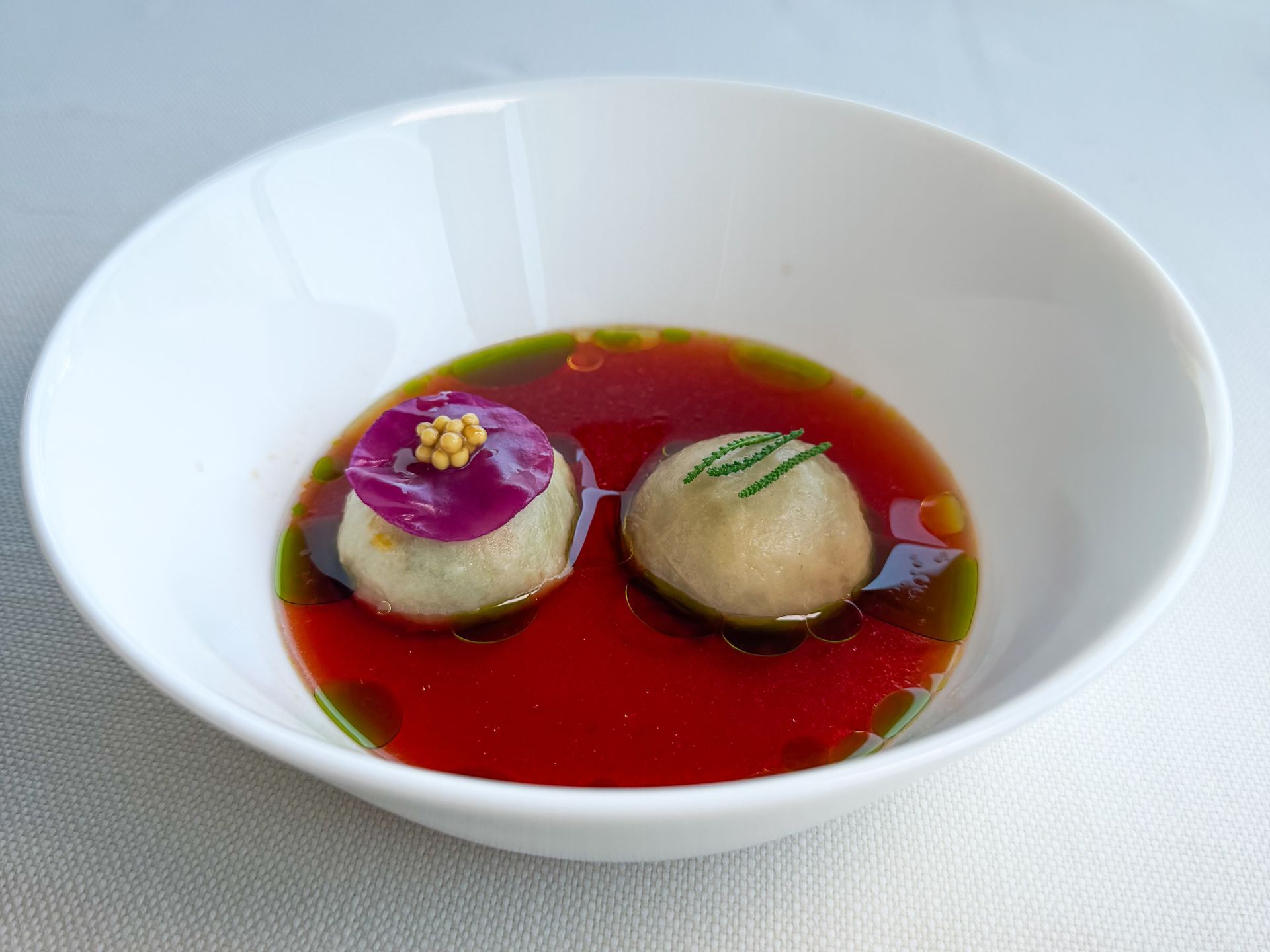 Bon bon con ragù di coda di manzo, cavolo viola marinato e brodo di bosco.