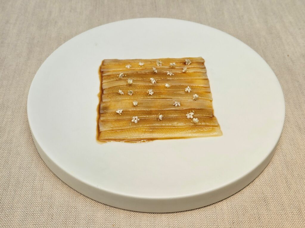 Asparago bianco, crema soffice ai fiori di sambuco, i fiori di sambuco, acqua di pomodoro ristretta fino a sembrare una salsa di soia.