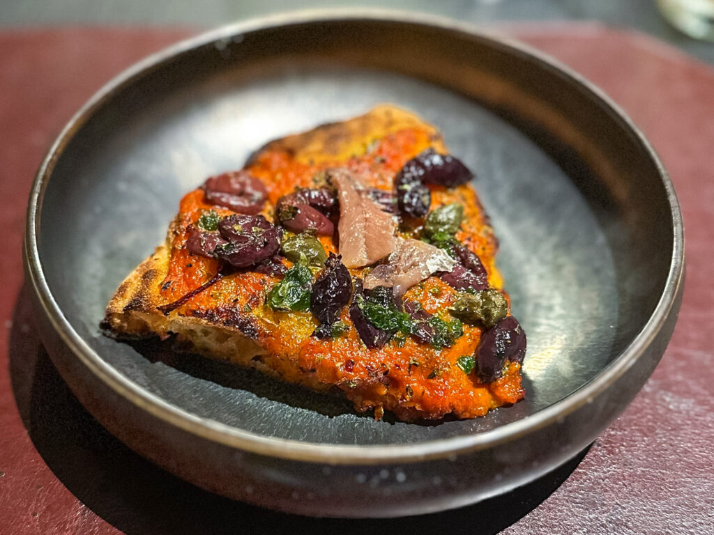 Futuro di Marinara: Crema di pomodoro arrosto, olive caiazzane, alici, pesto di aglio orsino, capperi di Salina, origano selvatico di Salina.