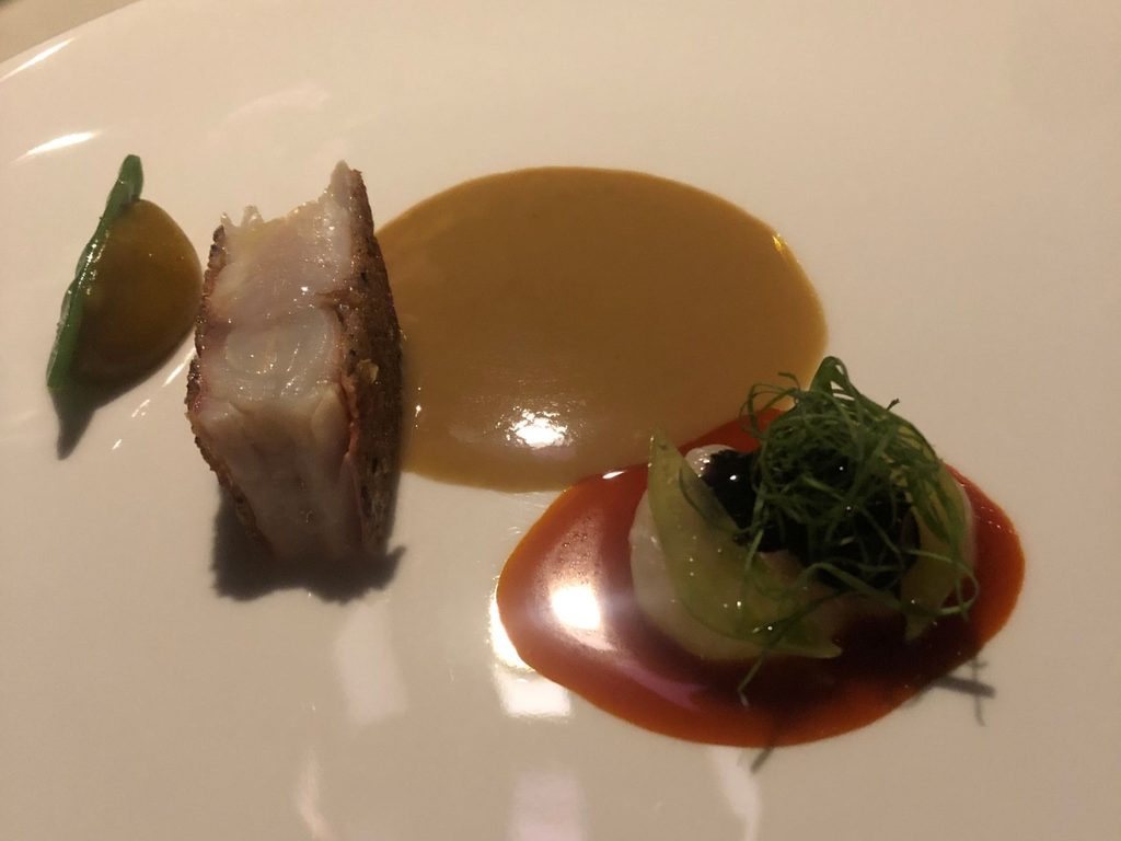 Triglia cotta in crosta di pane con crema di Lulo (tipo pomodoro più citrico), taccola, salsa allo zafferano, gambero gobbetto, nero di seppia e salsa di arachidi