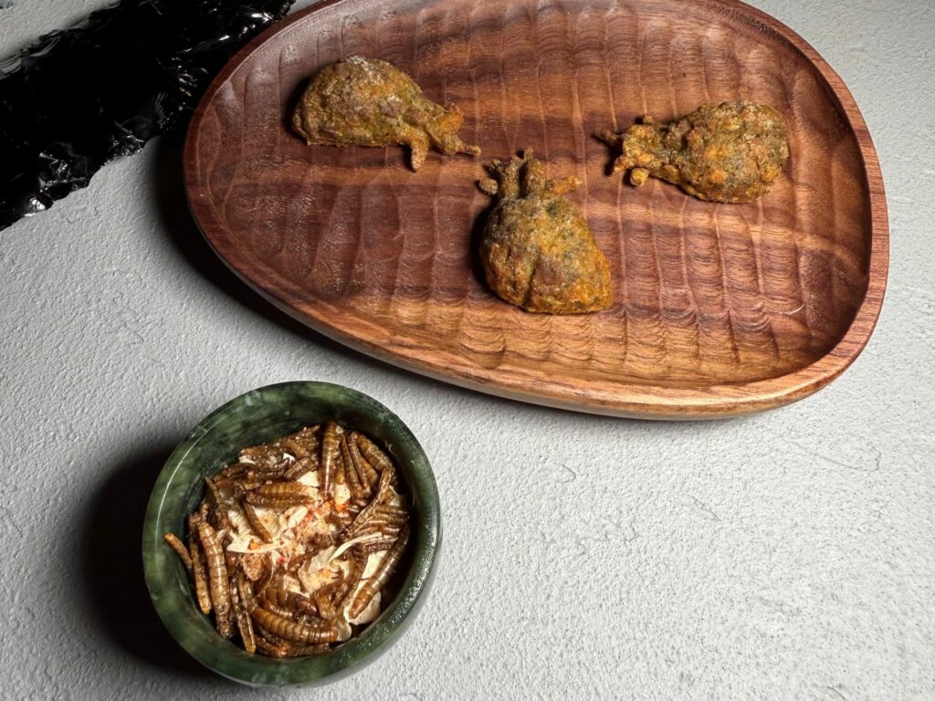 Cuore di pollo ricostruito come un curry thai, da pucciare in una salsa di cocco, yakiniku, pelle di pollo e larve croccanti.