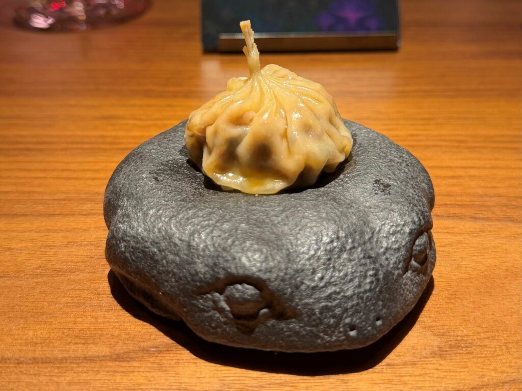 Raviolo al vapore con coscette di rana, cardoncelli e salsa XO di funghi .